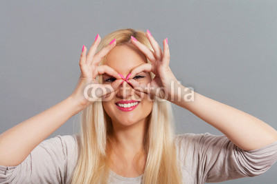 Portrait of a young woman framing her eyes with hands.