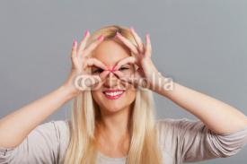 Fototapety Portrait of a young woman framing her eyes with hands.