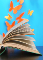 Opened book on wooden table on butterflies background