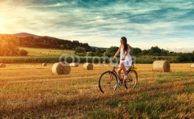 Fototapety Beautiful woman cycling on an old red bike, in a wheat field