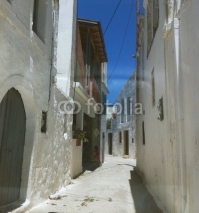 street of the small greek town with white walls and flowers