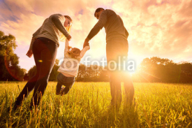 Parents hold the baby's hands.  Happy family in the park evening