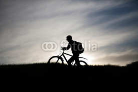 Naklejki silhouette of a cyclist on a mountain