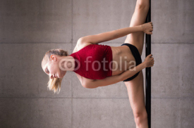 Naklejki Beautiful woman performing pole dance. Shot with industrial concrete background.