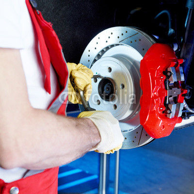 Motor mechanic is checking the brake of a car