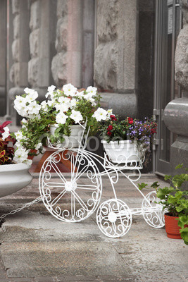 Decorative white bicycle with flowers standing on the street of the town.