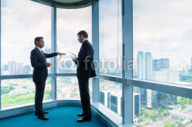 Businessmen standing in front of office window