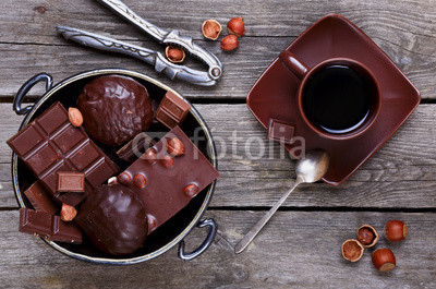 Chocolate in a metal vase, coffee and nuts on a gray wooden back