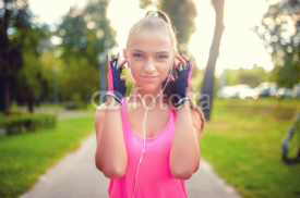 Fototapety smiling blonde girl training at dusk in urban park and listening
