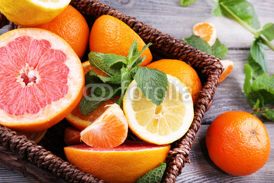 Fresh citrus fruits with green leaves in wicker basket