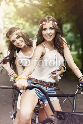 Two boho girls riding a bike