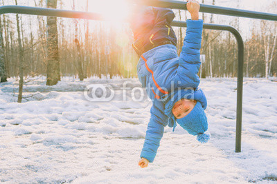 little boy playing on monkey bars in winter