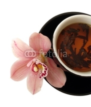 cup of tea with pink orchids on black plate isolated