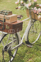 Naklejki Vintage bicycle on the field with a basket of flowers
