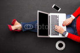 Woman sitting on ground at the office with computer in her lap 