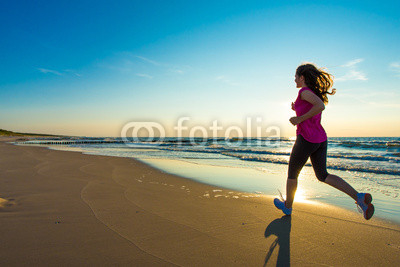 Teenage girl running, jumping on beach