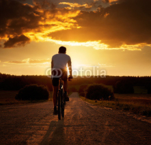 Naklejki Man Riding a Bicycle at Sunset