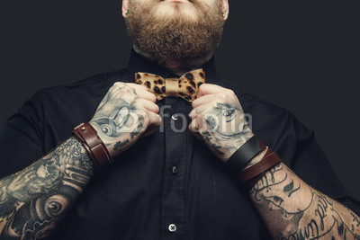 Bearded male with tattooes on his arms.