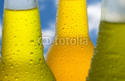 Three wet bottles with a sky in the background