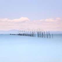 Fishing poles and soft water on sea landscape. Long exposure.
