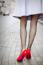 Fototapety Woman wearing red high heel shoes in city