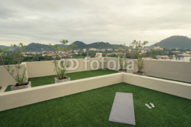 Morning yoga exercise concept. Mat on the green grass on the roof top with beautiful city view.