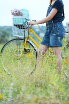 Fototapety Young woman with bicycle in meadow