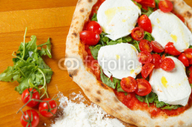 Naklejki Typical Italian Pizza, ingredients in background on wood table