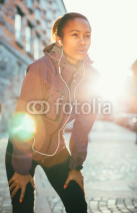 Fototapety Tired young woman catching breath after a long run in city