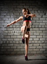 Naklejki Muscular woman on brick wall (normal version)