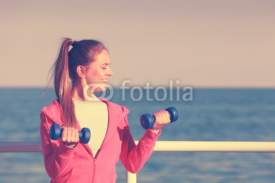 Fototapety Woman doing sports outdoors with dumbbells