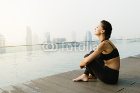 Relaxed young yoga woman in yoga pose near pool.