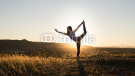 Woman doing yoga dancers pose during sunset