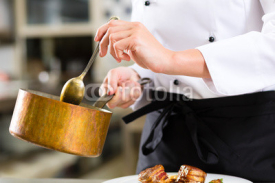 Naklejki Female Chef in restaurant kitchen cooking