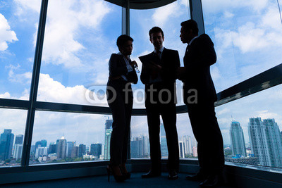 Businesspeople standing at office windo working