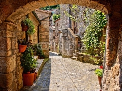 Arched cobblestone street in a Tuscan village, Italy