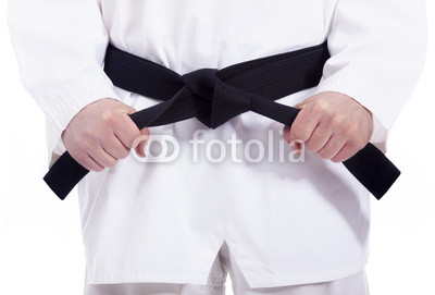 Martial arts man tying his black belt, isolated on white