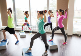 group of people with dumbbells and steppers