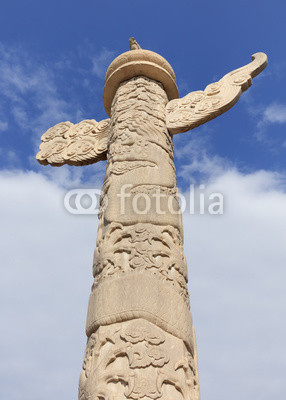 Ornate ancient stone pillar against a blue sky with clouds, Beijing, China