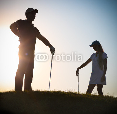 Male and female golfers at sunset