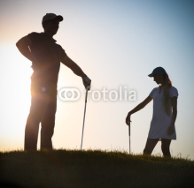 Fototapety Male and female golfers at sunset