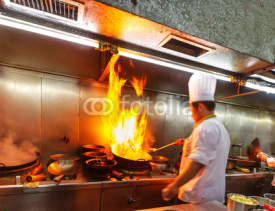 Chef in restaurant kitchenm, doing flambe on food