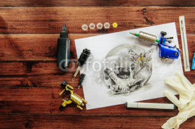 skull tattoo sketch with rotary machines, needles, grips on wooden background