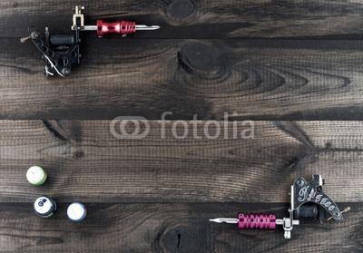 Tattoo machines and three bottles of ink isolated on wooden background. Tattoo guns.