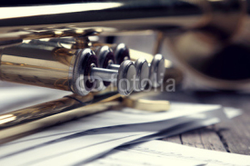 Trumpet and sheet music on old wooden table. Vintage style.