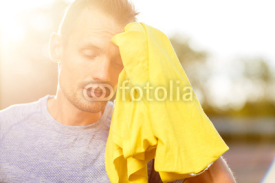 Tired athletic man wiped towel after workout