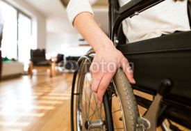 Young disabled woman in wheelchair at home in living room.