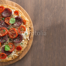 Italian pizza with salami and tomatoes on a wooden table