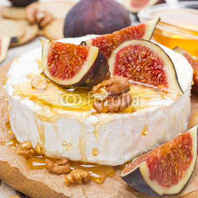 Camembert cheese with honey, figs and crackers on wooden board