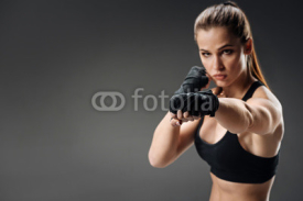 Powerful woman boxing on a grey background